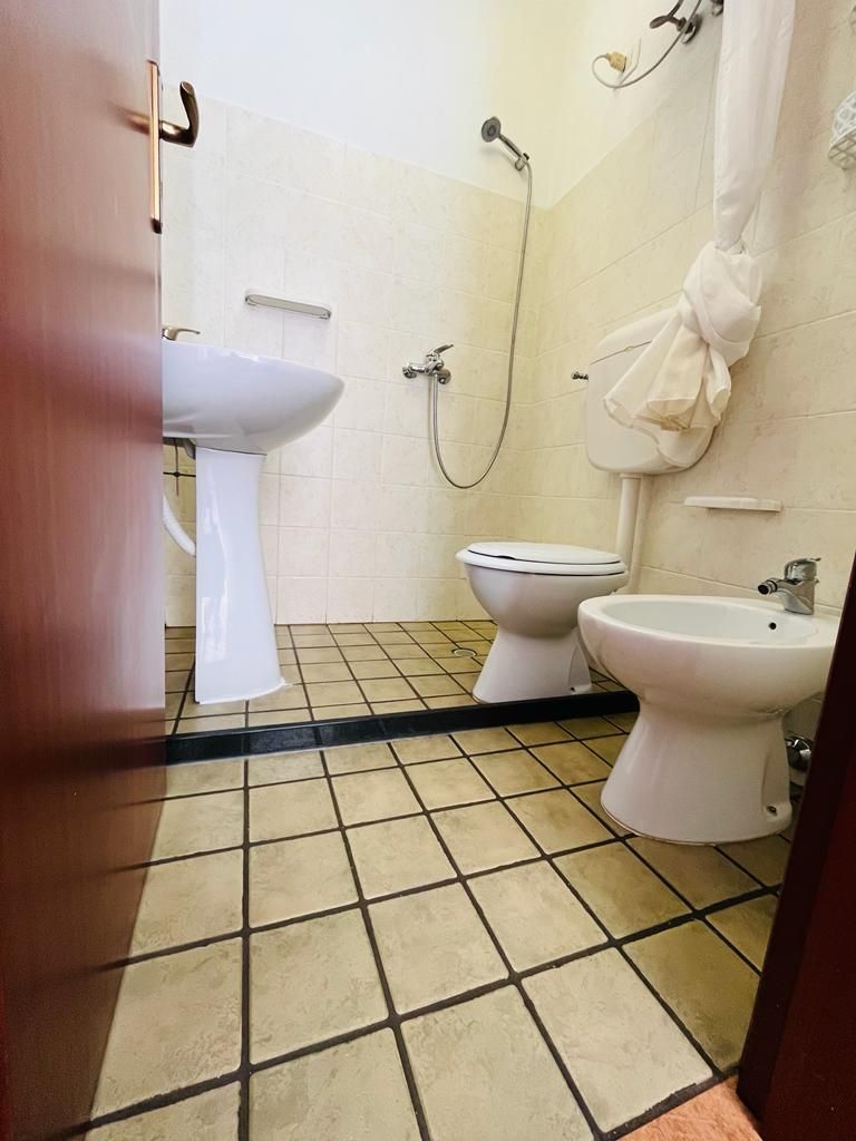 A bathroom with a sink, two toilets, and a bidet.