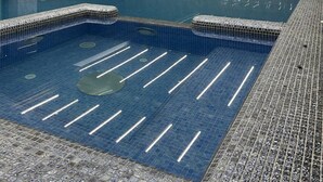 A swimming pool with a tiled floor and a ceiling with linear lighting fixtures.