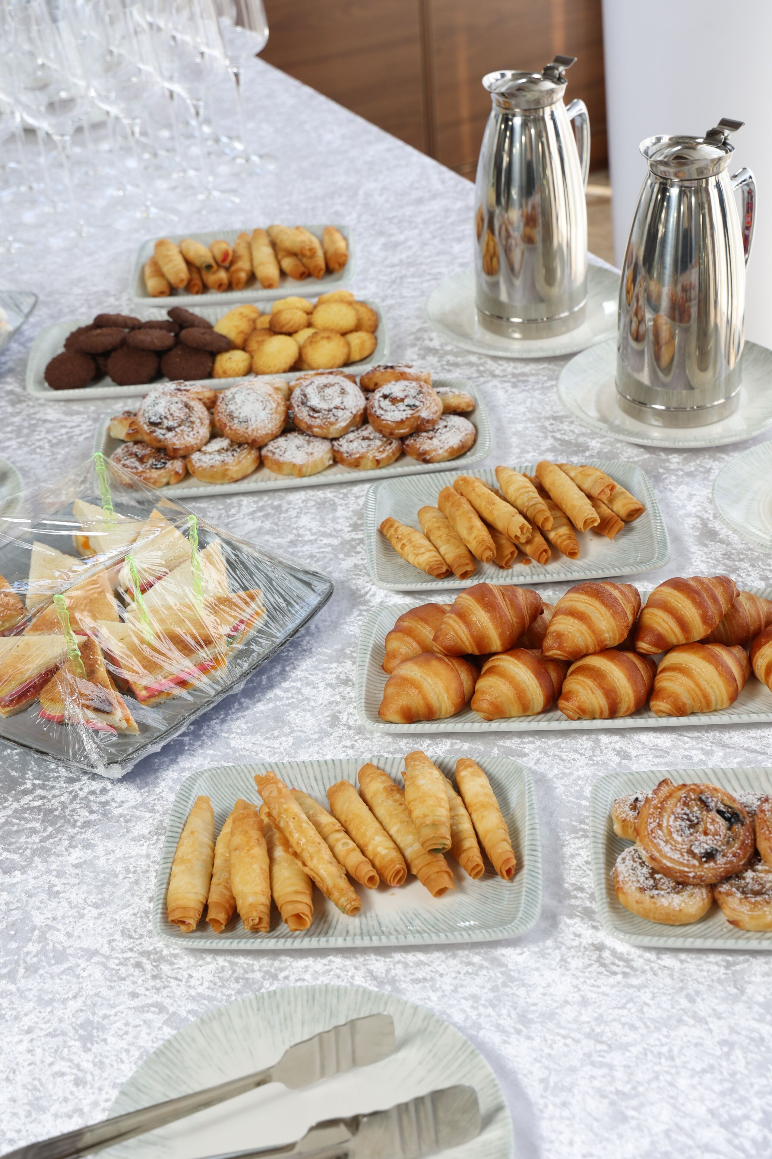Een buffet met diverse gebakjes en desserts, zoals croissants, koekjes en ander gebak.