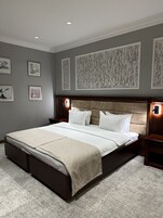 Un dormitorio ordenado con una cama grande, obras de arte enmarcadas en las paredes y cabecera con iluminación integrada.