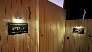 Wooden gates with signs for 'The Retreat' and 'The Cottage' at Coolum Beach. - Spa,Fire Pit,Cinema - The Cottage Coolum Beach (Coolum Beach)