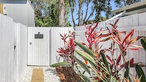 A fenced backyard with a gravel path leading to a gate. - Spa,Fire Pit,Cinema - The Cottage Coolum Beach (Coolum Beach)