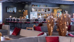 A modern bar area with sofas, bar stools, and a variety of bottles on shelves.