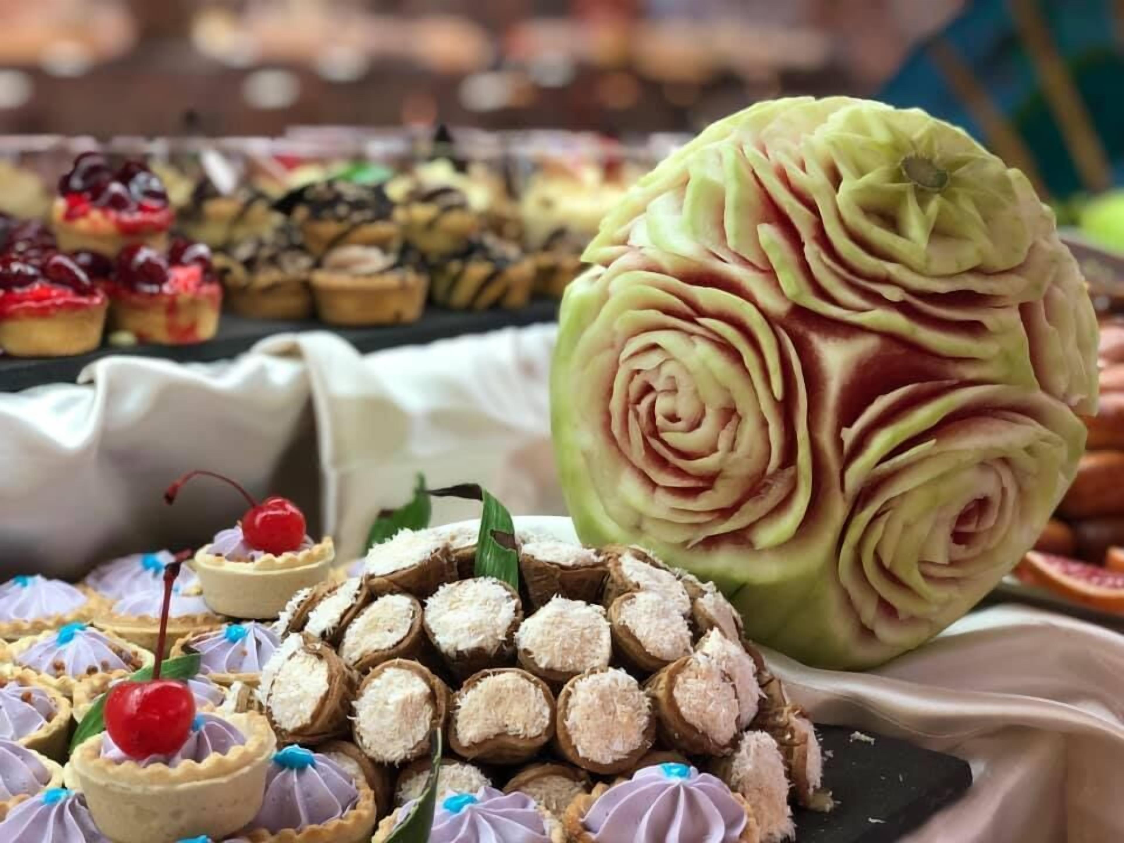 A variety of desserts, including a large intricately carved cake and smaller pastries.