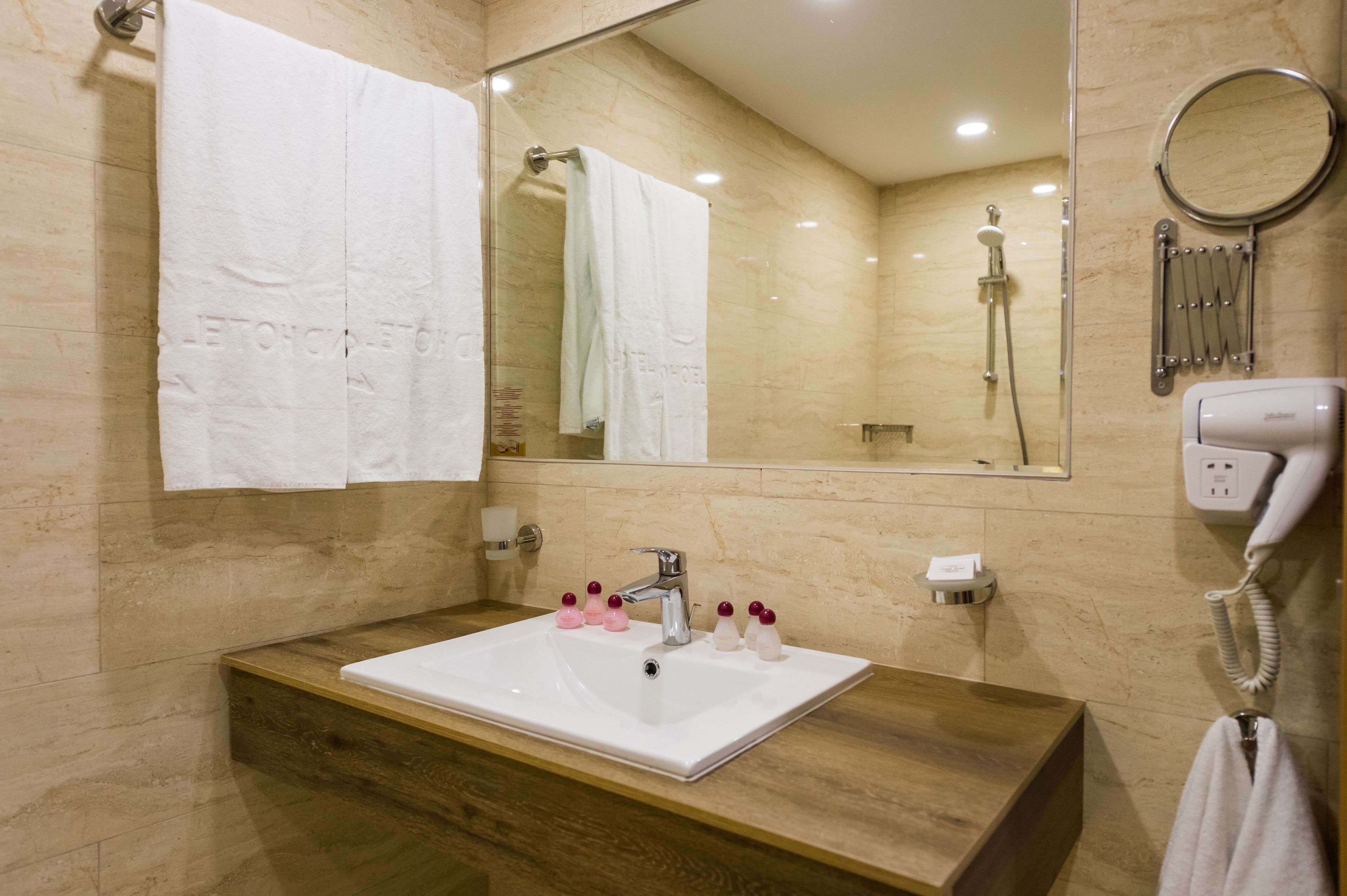 Un baño con lavamanos blanco, un espejo, un cabezal de ducha de mano y un teléfono.
