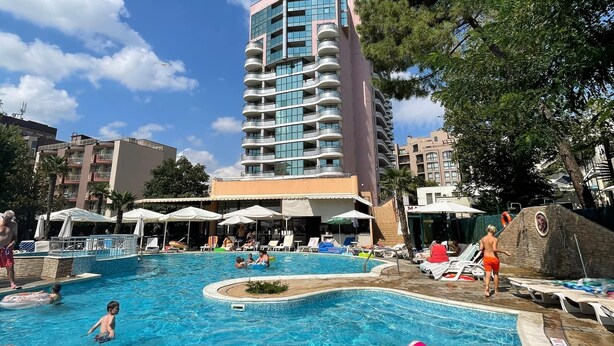 A swimming pool area with a hotel building in the background.