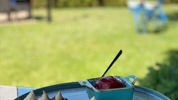 A dessert plate with a blue ceramic bowl containing a red sauce and a spoon, placed on a blue ceramic plate.