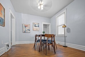 Un coin repas avec une table ronde et quatre chaises, un ventilateur de plafond et un lampadaire.