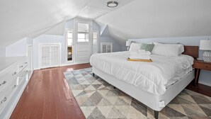 A bedroom with a large bed, a dresser, a nightstand, and a window. - Dog-Friendly | Yard & Office (St. Louis)