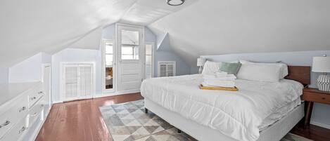 A bedroom with a large bed, a dresser, a nightstand, and a window.