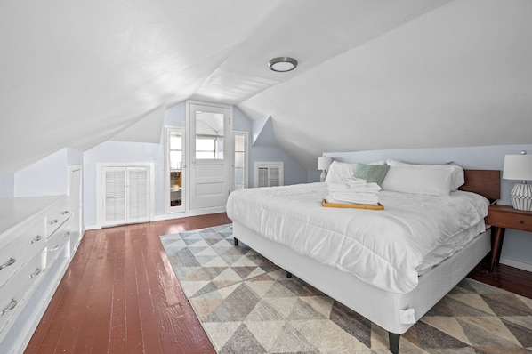 Une chambre à coucher avec un grand lit, une commode, une table de chevet et une fenêtre.