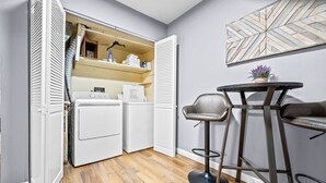 Une petite buanderie comprenant un lave-linge, un sèche-linge et une petite table avec une chaise.