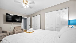 Une chambre d’hôtel dotée d’un grand lit, d’une télévision à écran plat, d’un ventilateur de plafond, d’un bureau avec une lampe et d’une chaise.