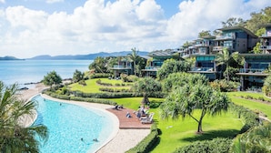 A resort with a swimming pool, beach, and lush greenery.