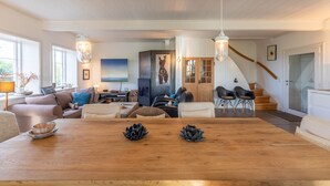 Un salon spacieux avec une table à manger en bois, des sièges confortables et un escalier menant à un autre niveau.