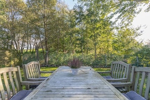 Surrounded by a lush garden, this outdoor space offers a central table and four chairs.