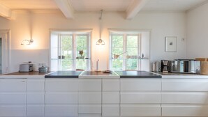 Une cuisine moderne avec des meubles blancs, un îlot central et des luminaires suspendus.