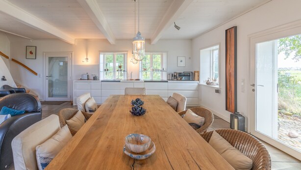 Un espace repas spacieux avec une table en bois, des sièges confortables et une vue sur l’extérieur.
