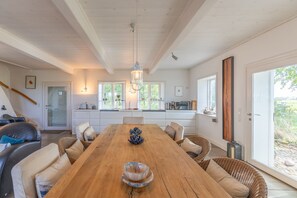 A spacious dining area with a wooden table, comfortable seating, and a view of the outdoors. - Vacation home Andrea in Aventoft for up to 4 people (Aventoft)