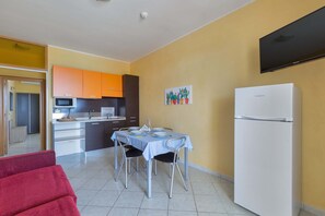 A compact kitchen with a dining table, chairs, and a refrigerator.