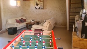 Ein Wohnzimmer mit einer Fußballstoßkicker-Tisch, zwei Sofas, einem Couchtisch und einem Wandposter.