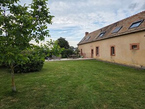 A building with a sloped roof, multiple windows, and a grassy courtyard.