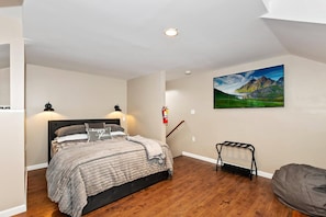 A bedroom with a bed, a mounted TV, a fire extinguisher, and a chair.