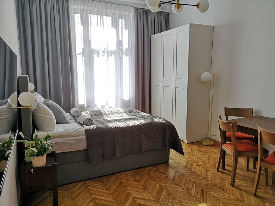 Une chambre à coucher moderne comprenant un lit, une table de chevet, une lampe, ainsi qu’un coin repas avec des chaises et une table.