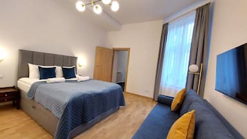 Ein modernes Hotelzimmer mit einem großen Bett, einer Couch, einem Fernseher und einem Kronleuchter.