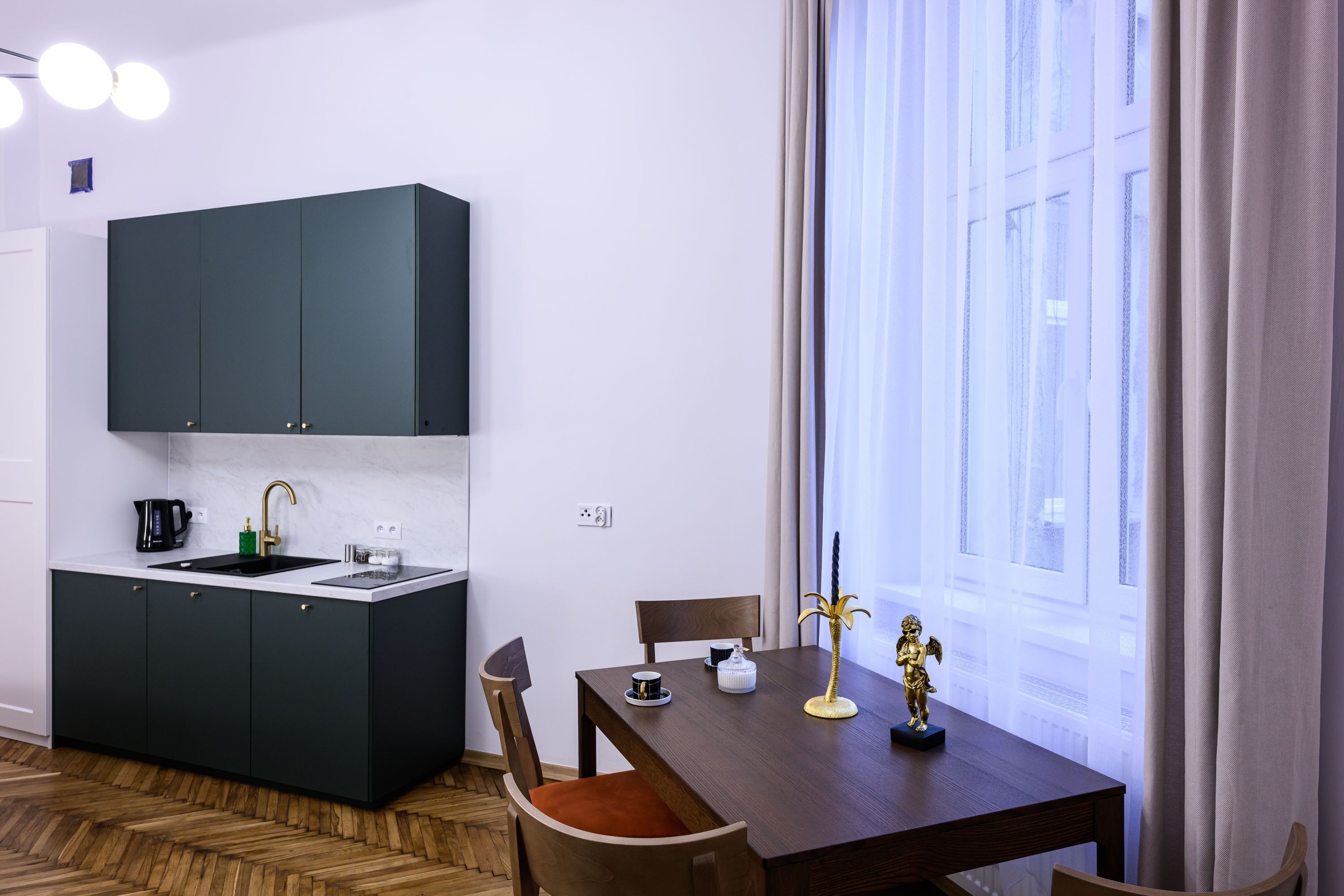 A modern kitchen with dark cabinets, a white countertop, and a dining area with a wooden table and chairs.