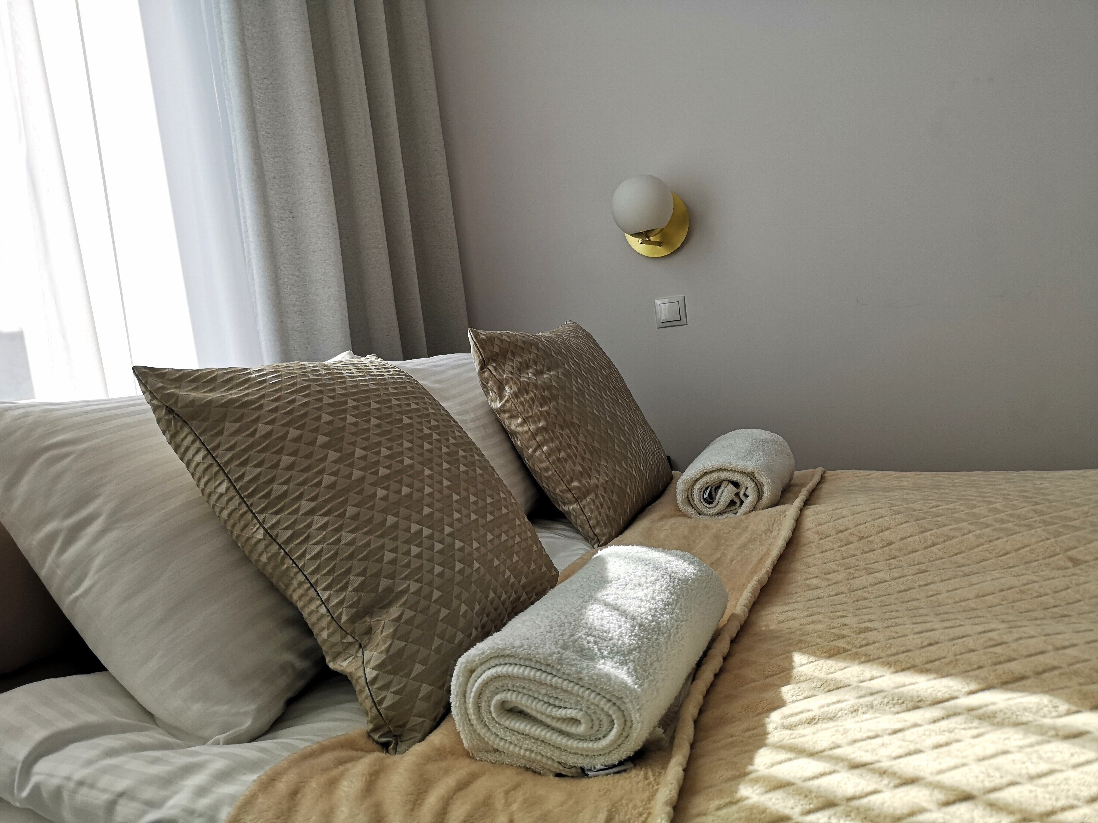 Un lit bien fait, avec des oreillers, une serviette enroulée et une couverture.
