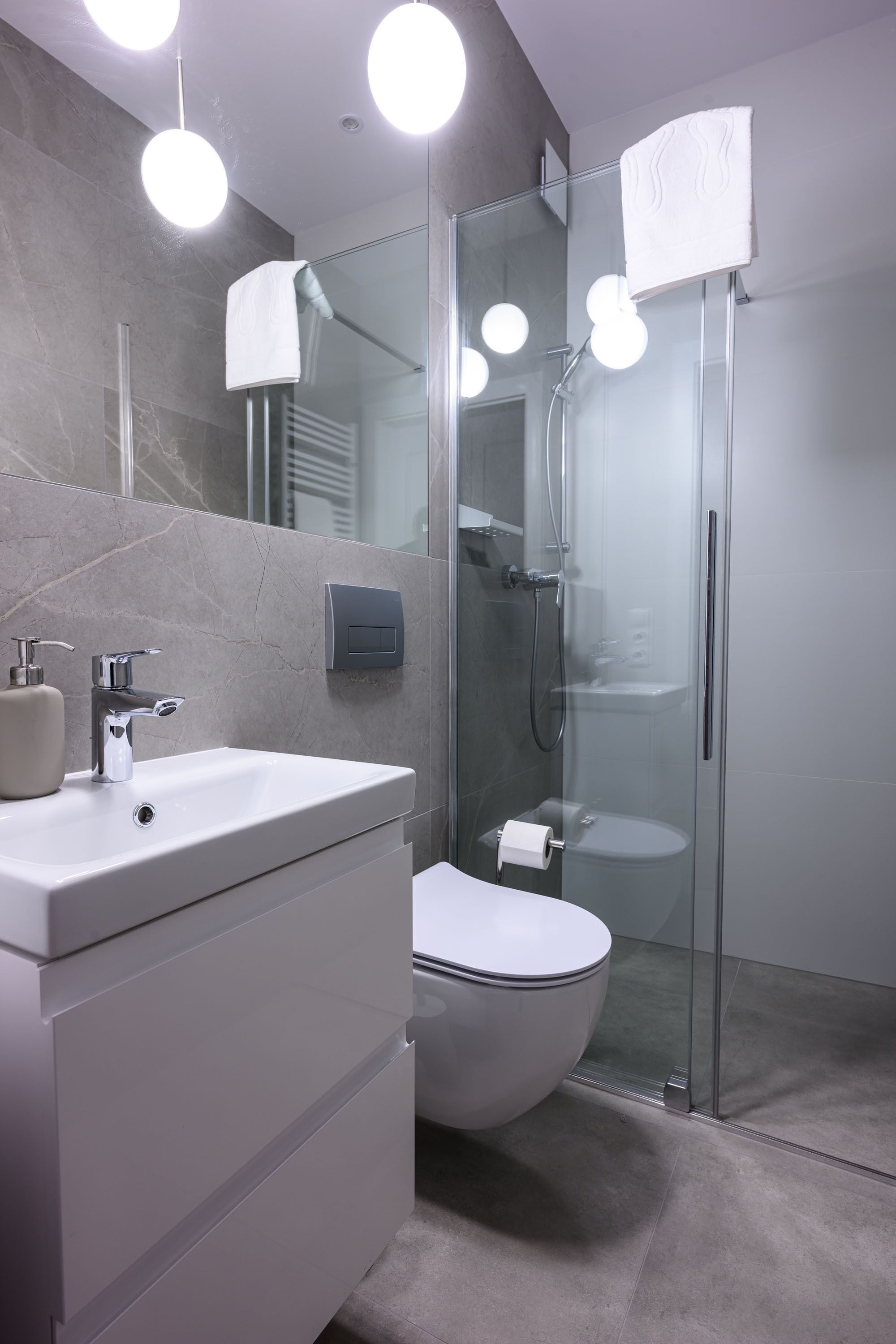 A modern bathroom with a glass-enclosed shower, a white sink, and a toilet.