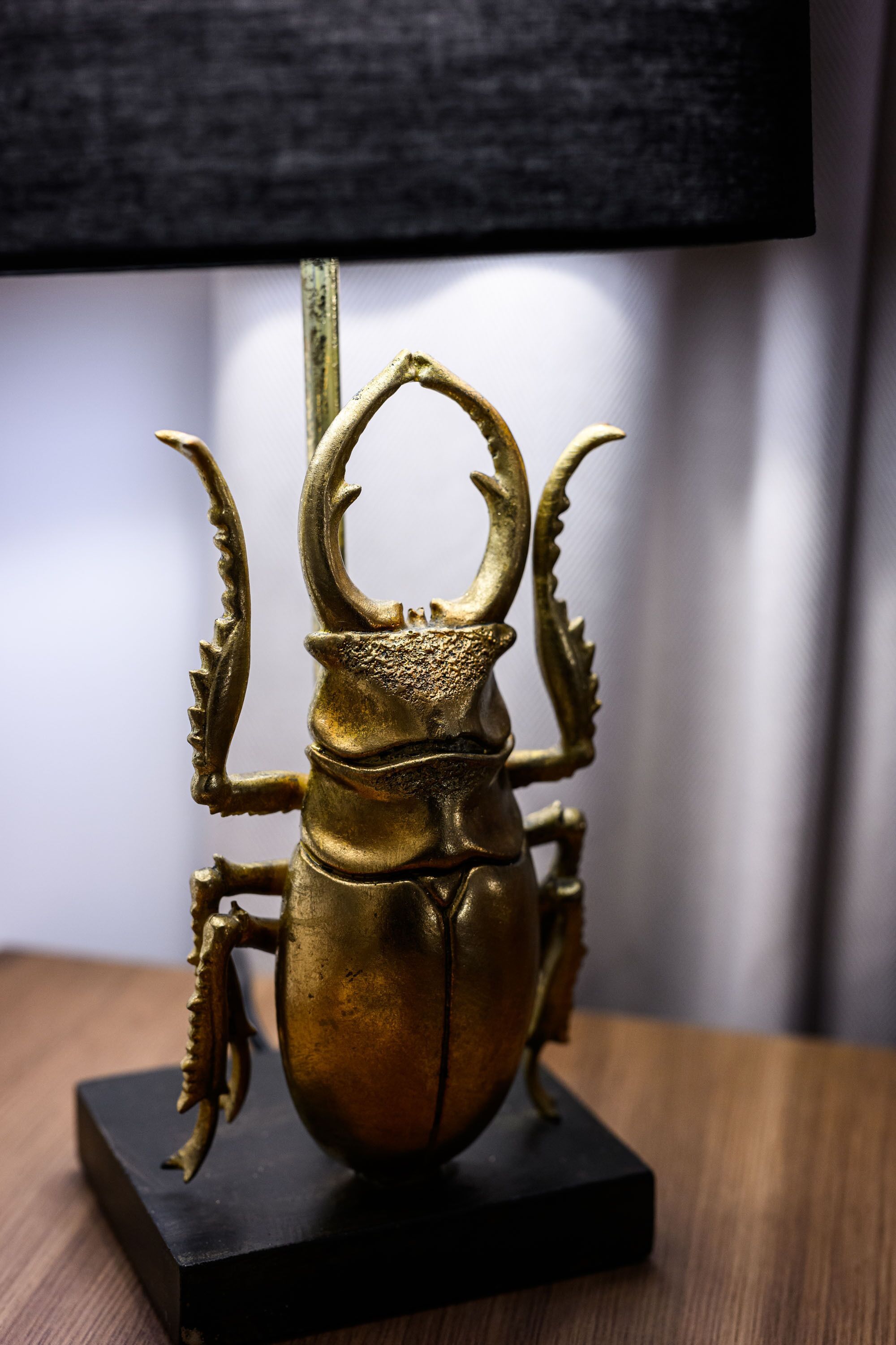 Une sculpture en laiton représentant un scarabée, posée sur un socle noir.