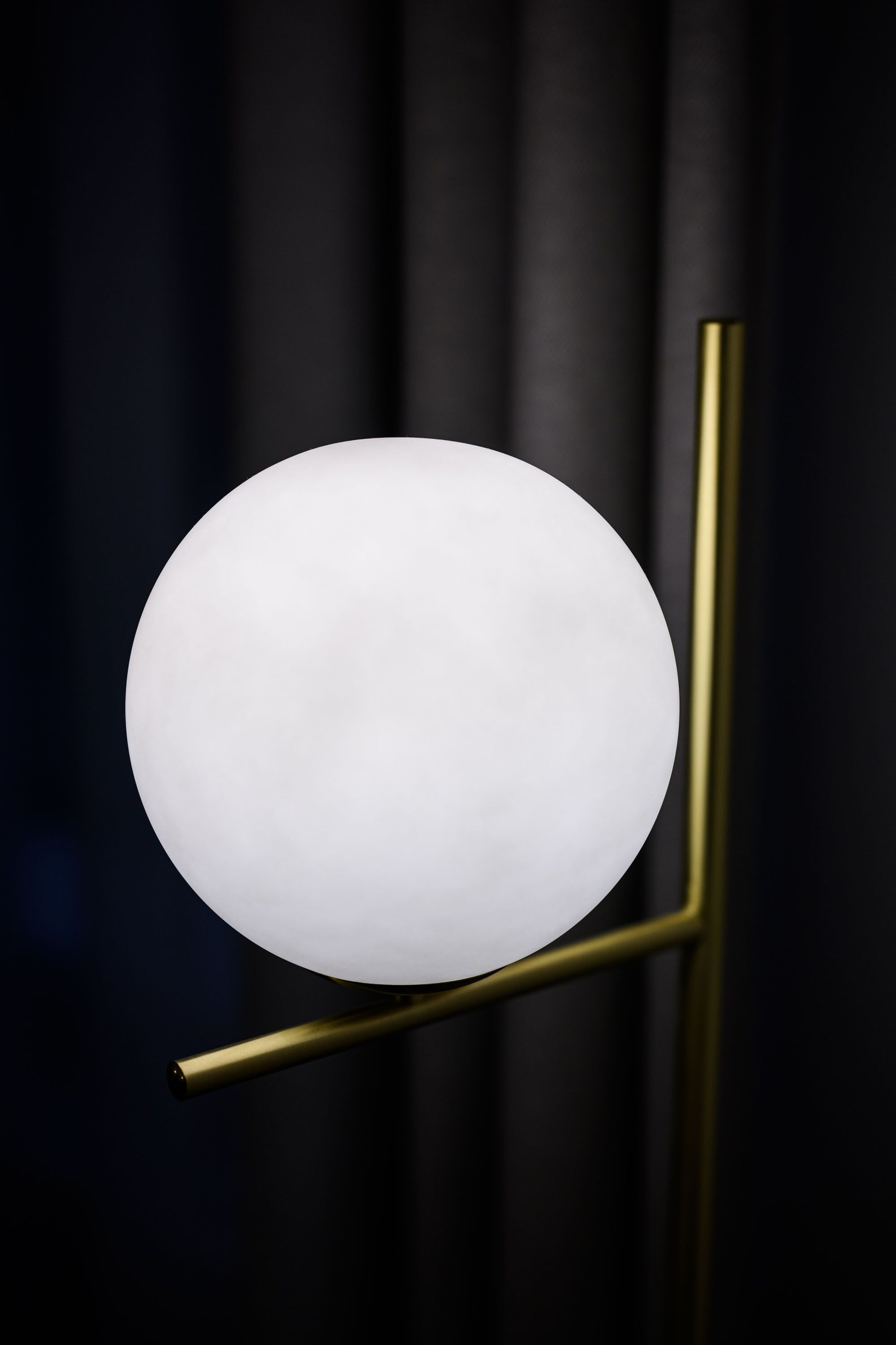 A modern spherical light fixture mounted on a gold-colored stand.