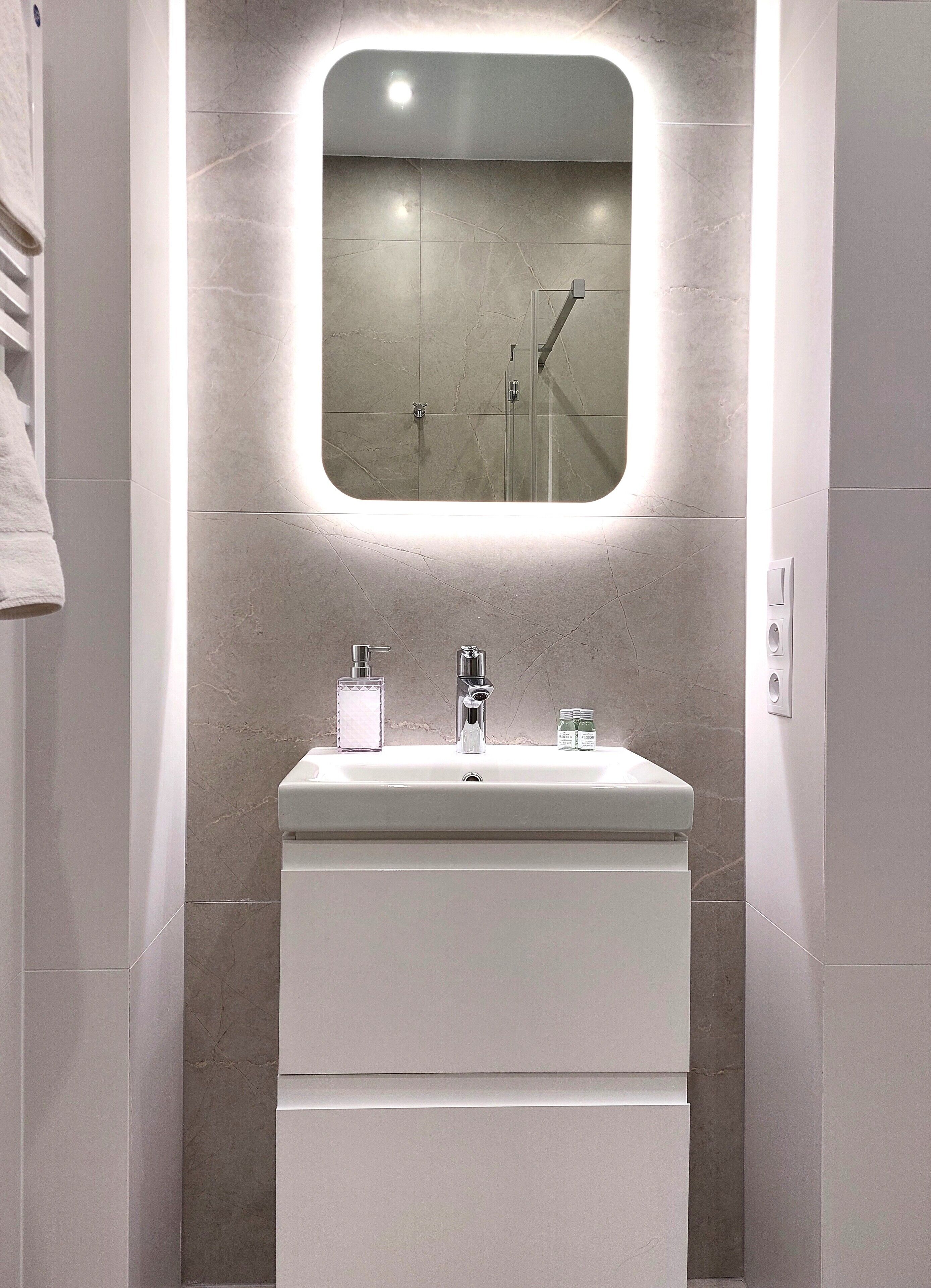 Un baño con un lavamanos blanco, un espejo y una ducha.