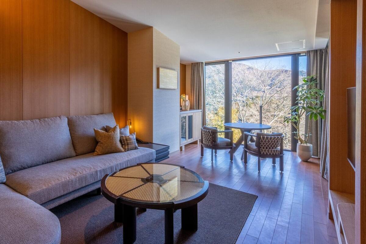 A modern living room with a sofa, a coffee table, and a dining area with chairs.
