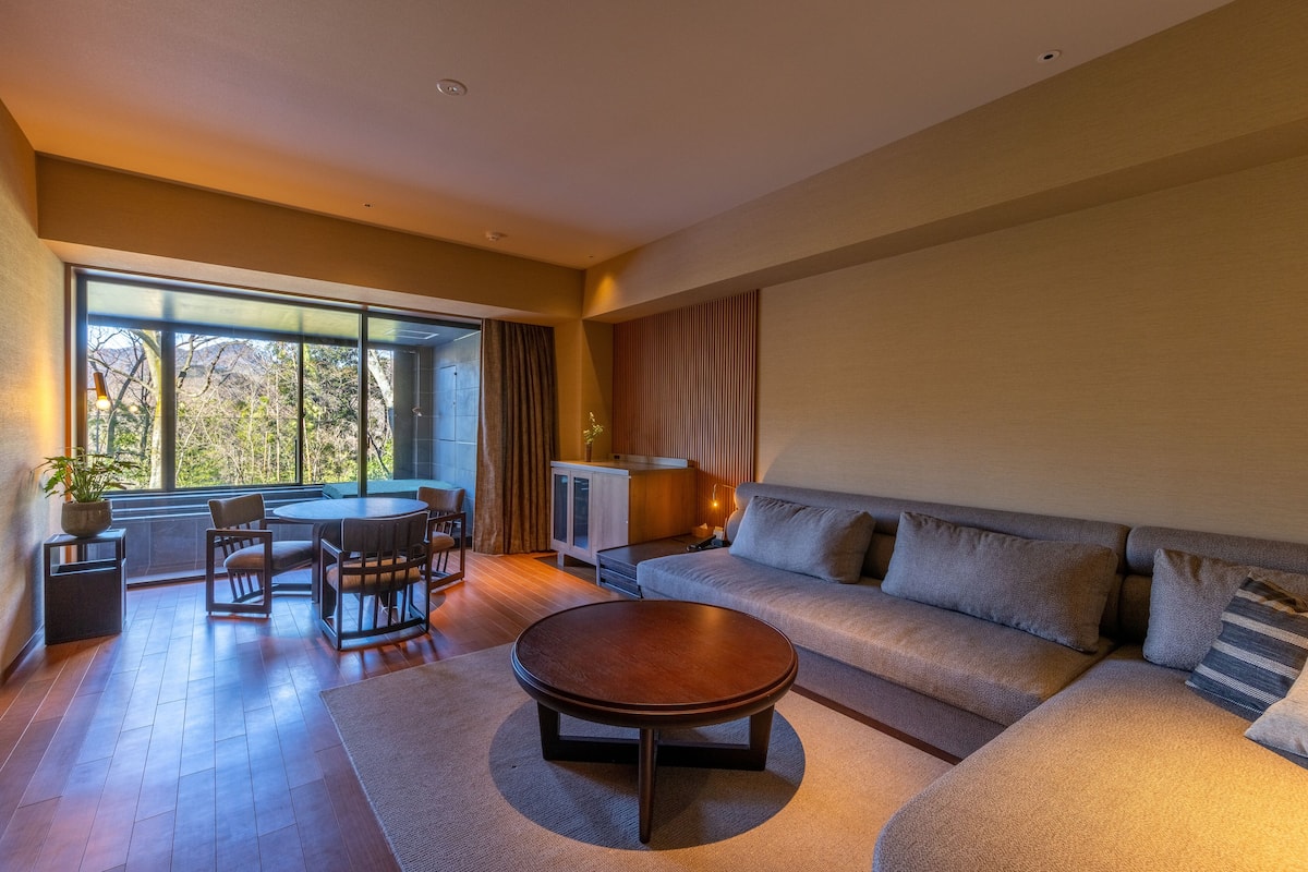 A modern living room with a sofa, a coffee table, and a dining area with chairs and a table.