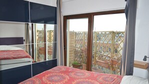 A bedroom with a large bed, a mirrored wardrobe, and a sliding glass door leading to a balcony with a wooden lattice fence. - Bright and well-connected penthouse (Roma)