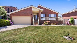 A two-story brick house with a front garage, a covered porch, and a well-maintained lawn. - Family Escape | Lakes Entrance Retreat (Lakes Entrance)