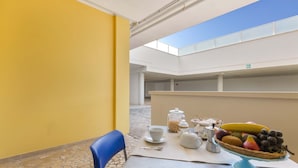 Un comedor con una mesa preparada para dos, una cesta de fruta y vistas al cielo a través de un tragaluz.