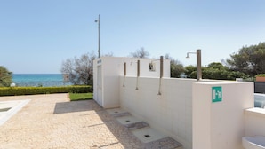 A portable restroom area with a tiled floor and a view of the sea.