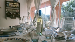 Une table à manger dressée avec différents types de verres et d’assiettes, une bouteille de vin et des objets décoratifs.