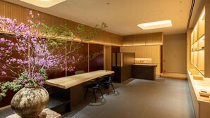 A modern interior with a wooden dining table, chairs, a vase with flowers, and a kitchen area. - Fufu Kyoto (Kyoto)