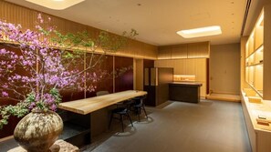 Un interior moderno con una mesa de comedor de madera, sillas, un florero con flores y una zona de cocina.