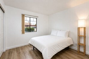 A bedroom with a bed, a window, and a floor lamp.
