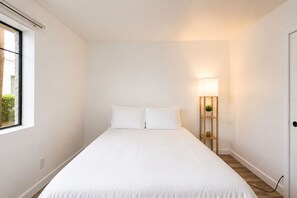 A bedroom with a bed, a bedside lamp, and a window.