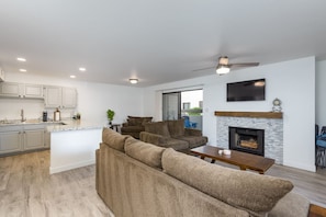 A modern living space with a kitchen, a seating area with sofas, a fireplace, and a flat-screen TV mounted on the wall. - Walkable 2BR in Old Town w/ Pool + More (Scottsdale)