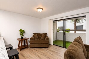 A modern living room with a brown sofa, a small wooden table, and a potted plant.