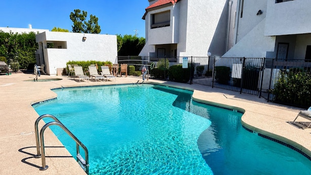 Une piscine à bord incurvé, entourée de chaises longues et d’une clôture.