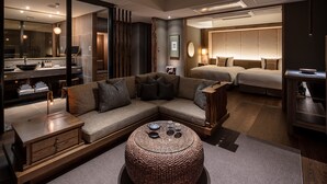 A modern hotel room with a large bed, a sofa, a round coffee table, and a bathroom with a large mirror and sink. - Fufu Nara (Nara)
